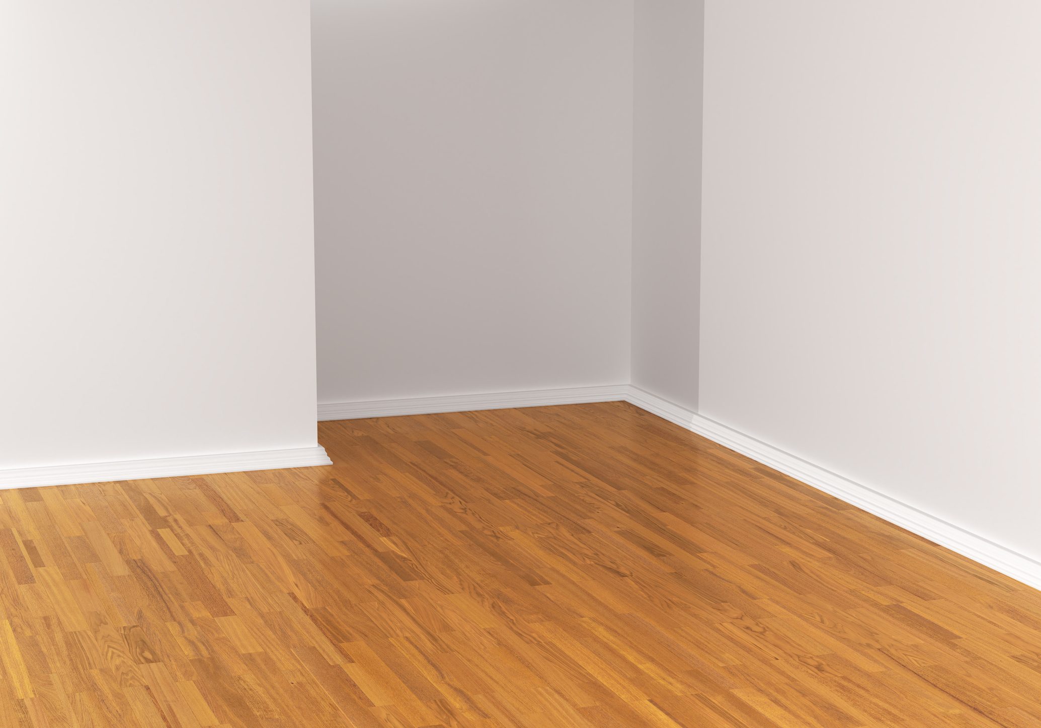 A wooden floor extends across the corner of a room, meeting plain white walls that create a minimalist and spacious environment.