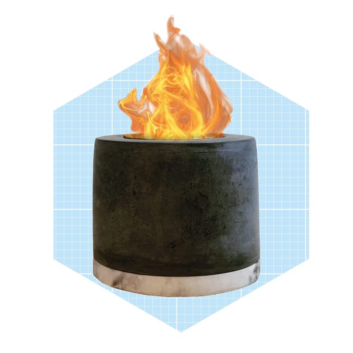 A cylindrical outdoor fire pit emits bright orange flames, set against a light blue grid background, providing warmth and ambiance.