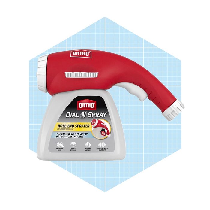A red hose-end sprayer dispenses liquid, designed for easy application of gardening concentrates, displayed on a light blue grid background.