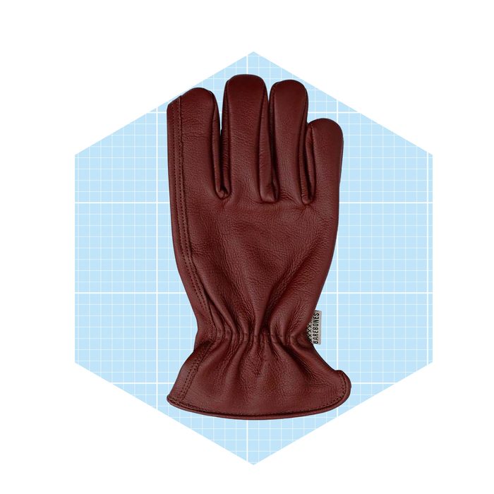 A brown leather glove rests flat on a light blue grid-patterned background, showcasing its five fingers and gathered wrist design.