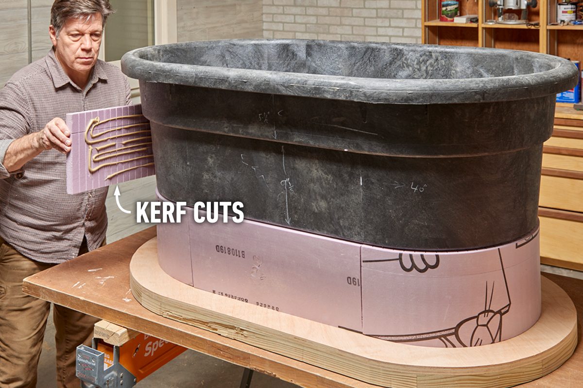 A person holds a board with adhesive, preparing to attach it to a curved container on a workspace surrounded by tools and materials.
