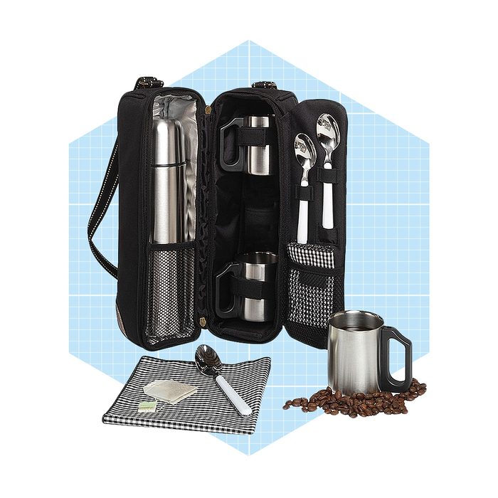 A black carrying case contains a thermos, two mugs, and utensils, arranged neatly against a light blue background, with coffee beans scattered nearby.