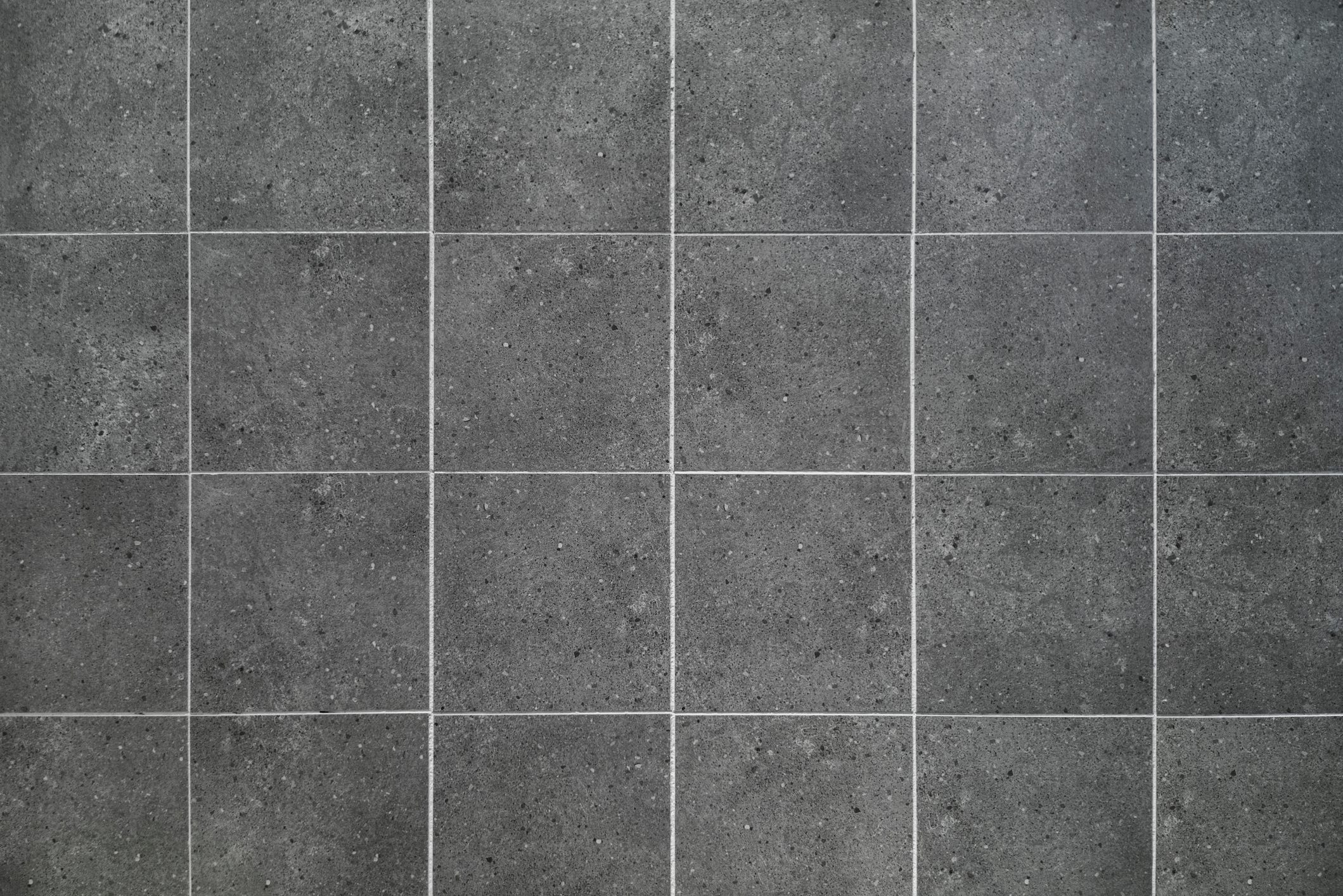 Gray tiles are arranged in a grid pattern, creating a uniform surface in a neutral, modern environment. The texture appears smooth with slight variations.