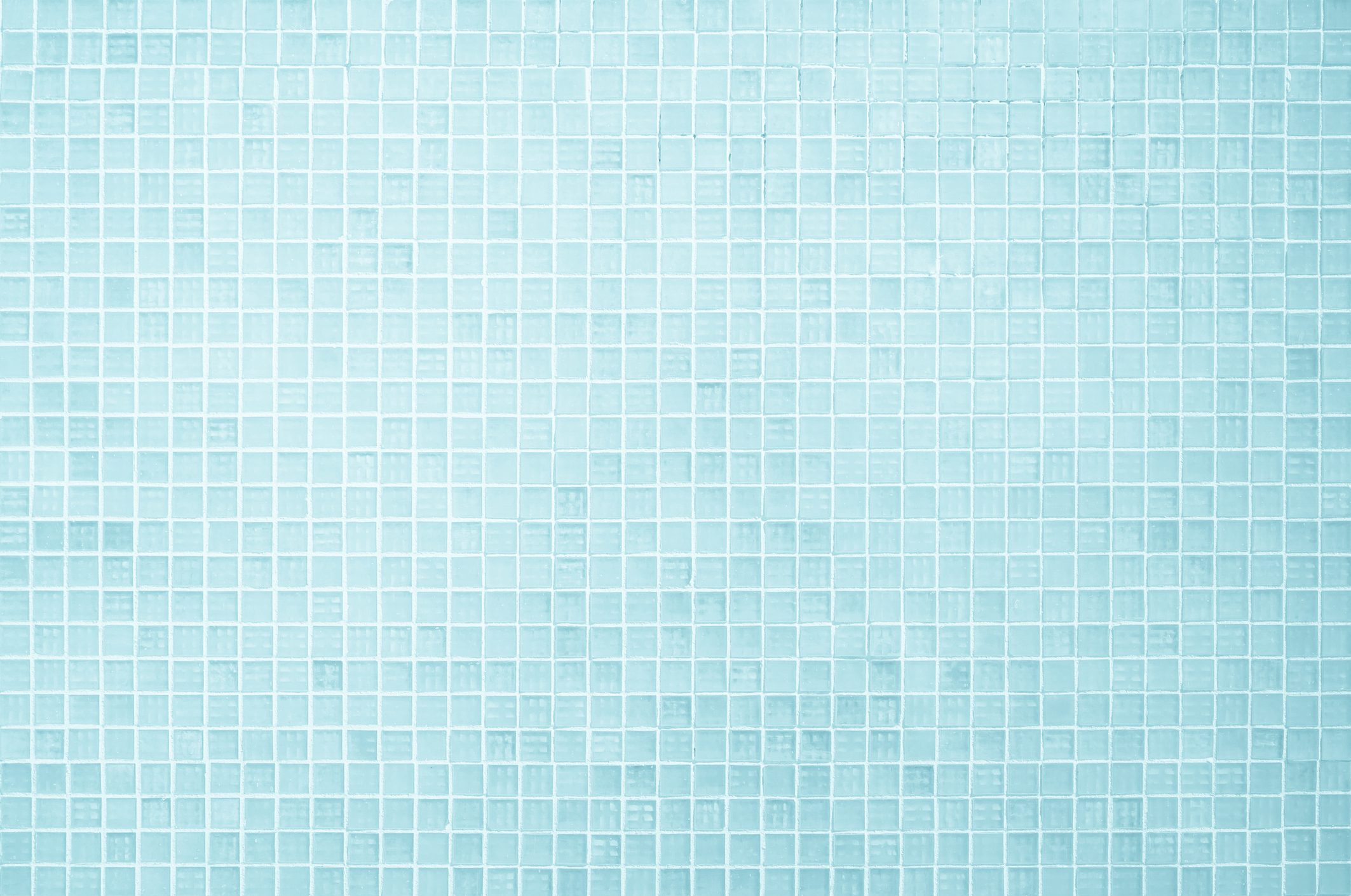 Square blue tiles cover a flat surface, creating a uniform, glossy texture in a light and serene setting.