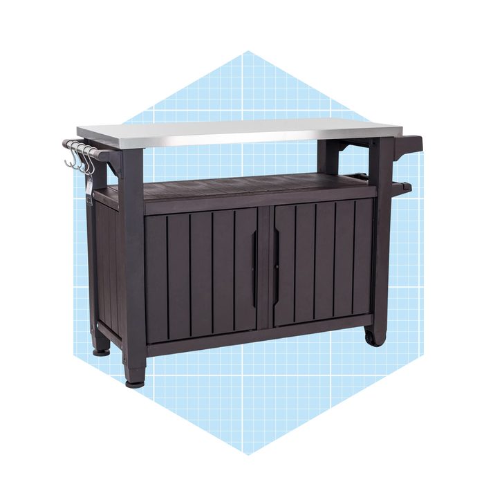 A dark wooden cabinet with a white countertop and three hooks is positioned against a light blue geometric background, suggesting a modern outdoor or kitchen setting.