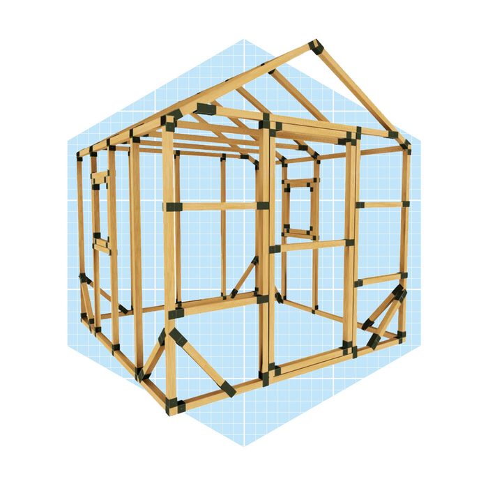A wooden frame structure is assembled, supported by braces. It appears as a partial house, set against a light blue grid background.
