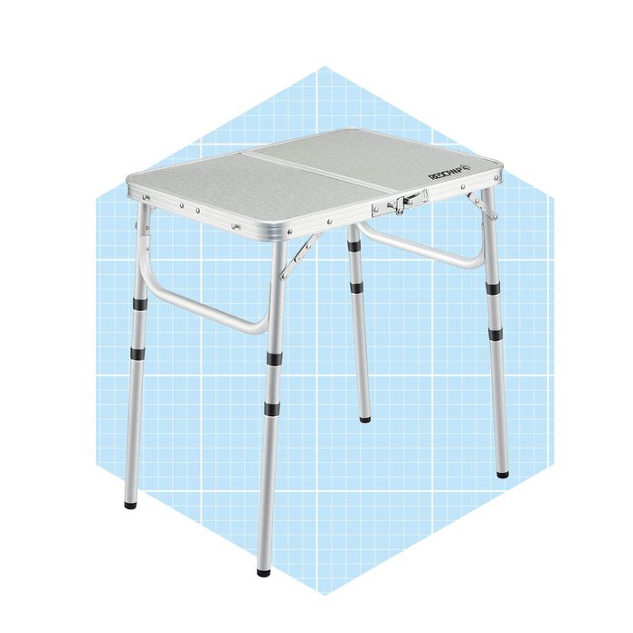 A foldable aluminum table stands with four legs. It is situated against a light blue grid-patterned background, ready for use in various settings.
