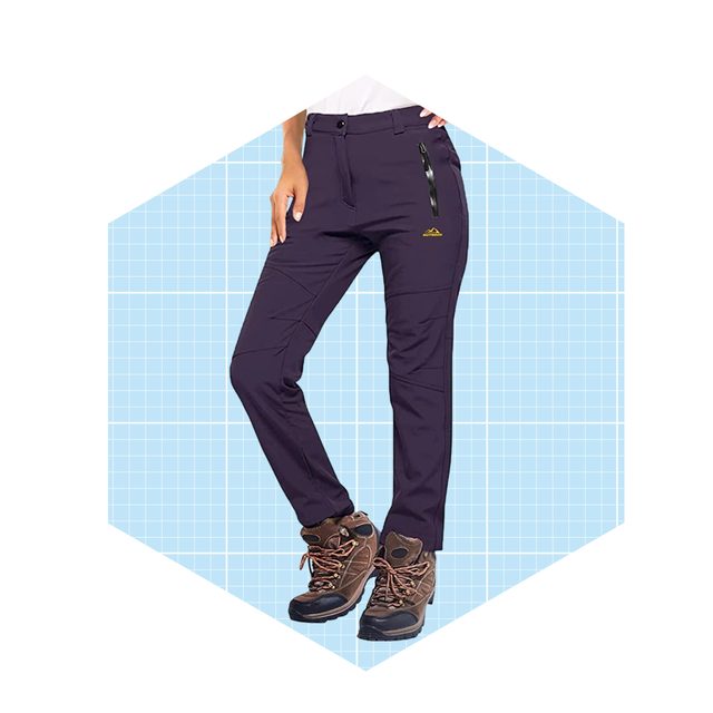 Dark purple hiking pants are worn by a person standing, with one hand on the hip, against a light blue grid background.