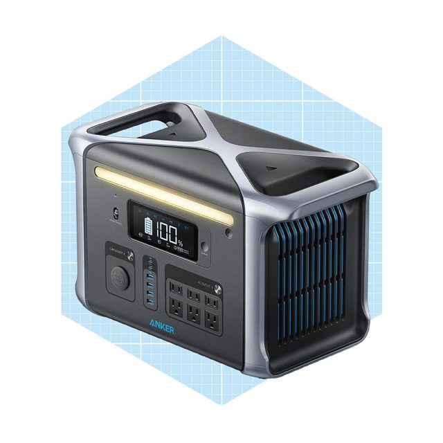 A portable power station is displaying a battery percentage on an LED screen, resting against a light blue grid background with a handle on top.