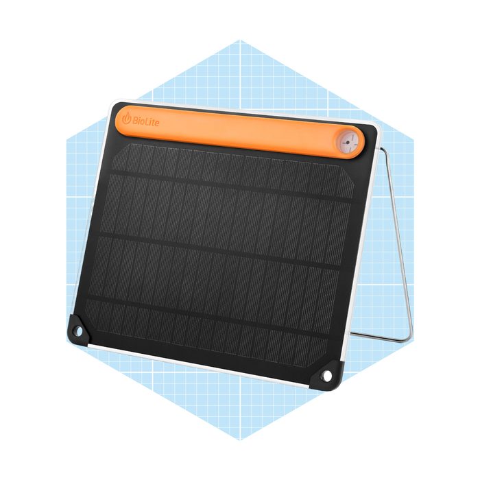 A solar panel stands upright, absorbing sunlight. It features a black surface with a distinctive orange top, set against a light blue grid background.
