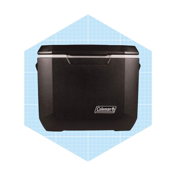 A black cooler sits upright, designed for outdoor use, against a light blue grid background, displaying the Coleman logo prominently on the front.