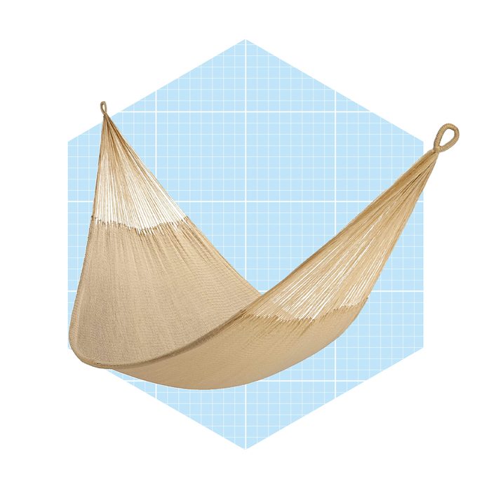 A beige hammock is suspended in a relaxed position against a light blue grid background, inviting rest and leisure.