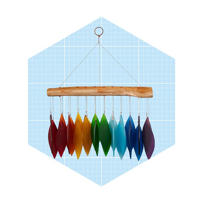 A colorful hanging mobile features leaf-shaped pieces swaying gently beneath a wooden bar, set against a light blue grid background.