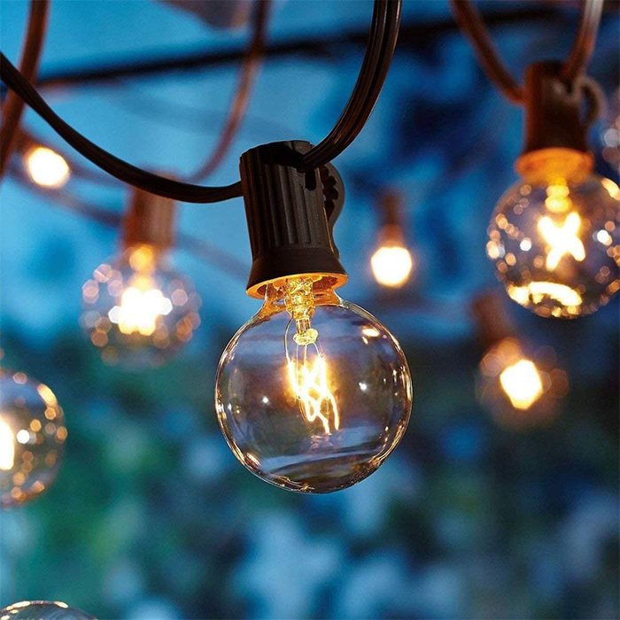 A glowing light bulb hangs from a string, illuminating a blurred, softly colored background, creating a warm, inviting atmosphere.