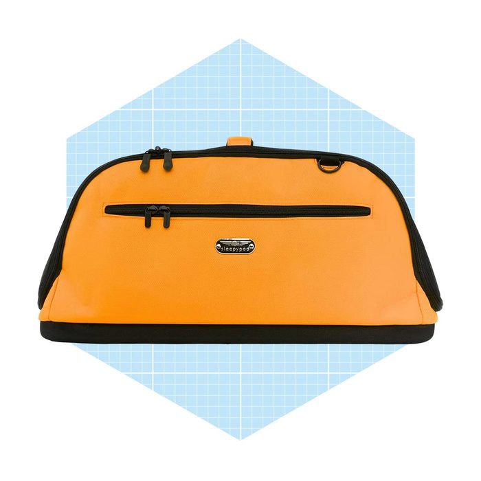 A vibrant orange bag rests against a light blue geometric background, featuring dual zippered compartments and a branded label, suitable for travel or storage.