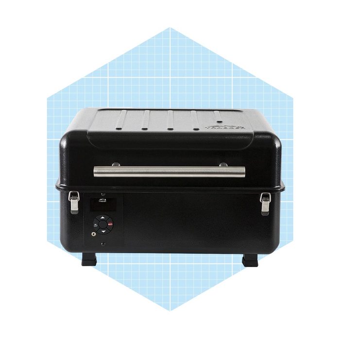 A black electric grill sits on a blue grid-patterned background, featuring control buttons and a stainless steel handle, designed for outdoor cooking.