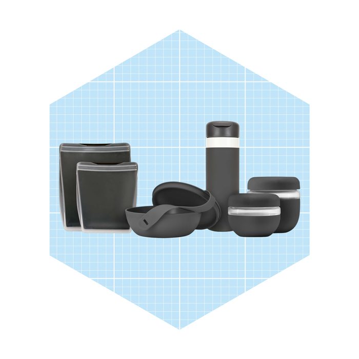 A collection of dark gray containers, including bowls and a thermos, arranged on a light blue grid background, suggesting organization or storage.