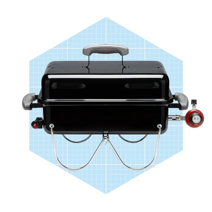 A black gas grill features a handle on top, connected to a gas supply with a pressure gauge, set against a light blue grid background.