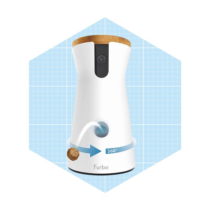 A smart pet camera device dispenses treats in a 360° arc, set against a light blue grid background, featuring a wooden top and a lens.
