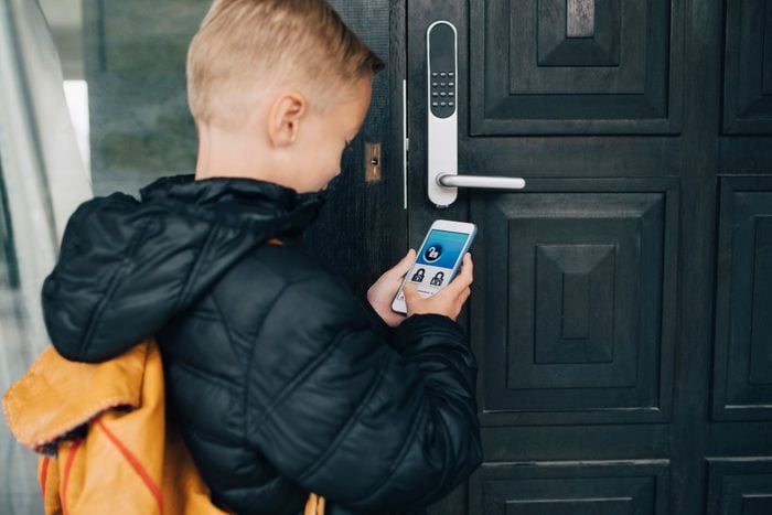 Rear view of boy using app on smart phone to unlock house door