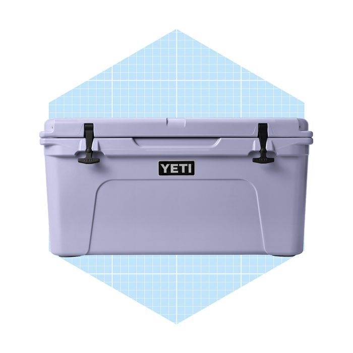 A gray YETI cooler sits prominently, secured with black latches, against a light blue grid background, suggesting a clean, modern aesthetic.
