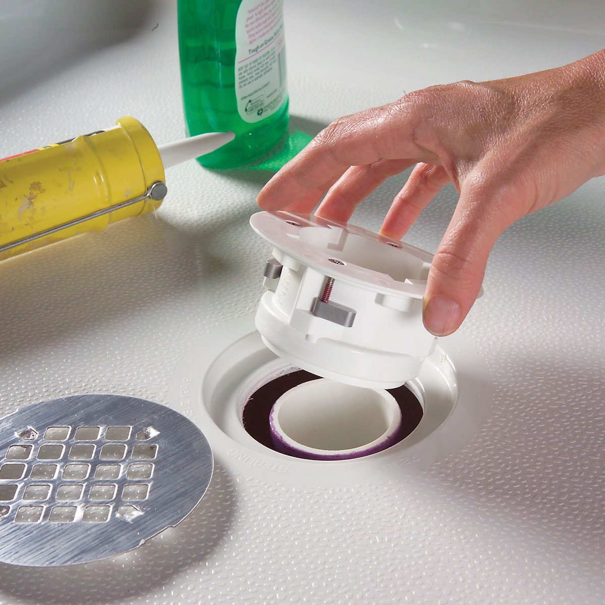 A hand holding a white plastic drain