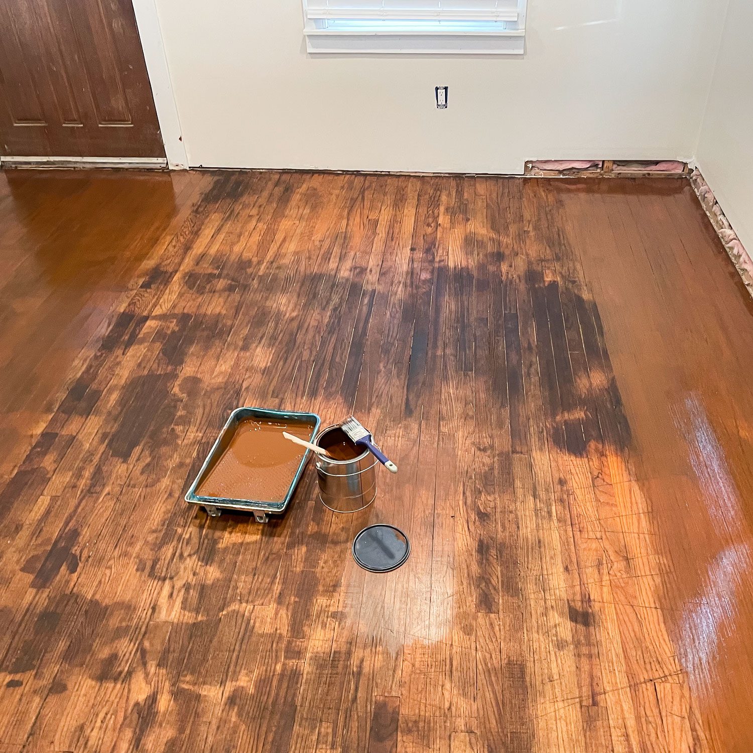 A Tray and Steel Container of Paint with Paint Brush on Hardwood Floor