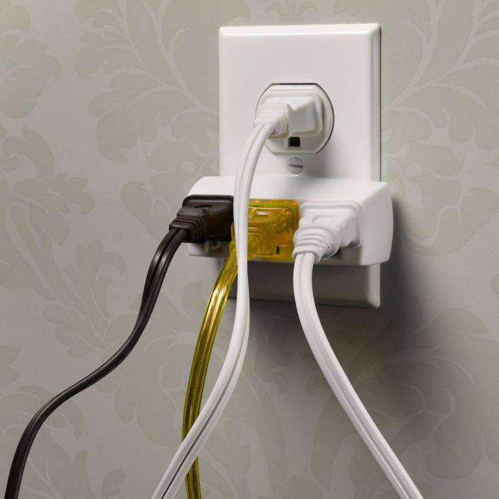 Electrical wall outlet overloaded with plugs, close-up