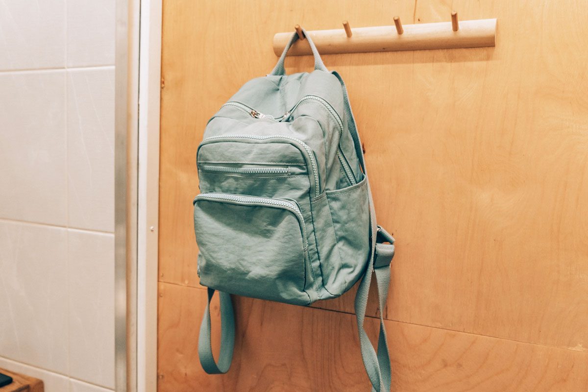 green backpack hanging on a hook