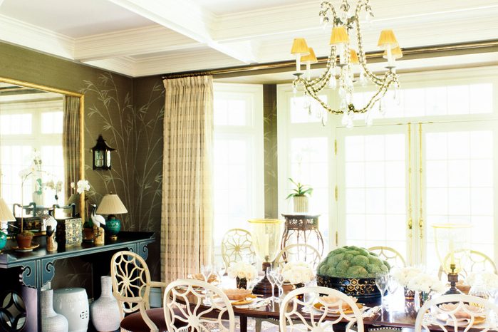Green plant, flowers and wineglasses are arranged on the dining table under the chandelier