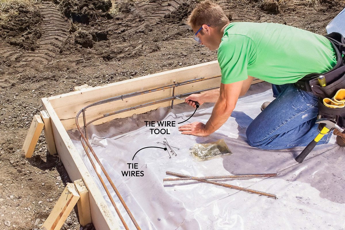 Wide shot; Step 5 Tie in the Rebar to Strengthen the Slab; Cover the fill with a layer of 6-mm plastic sheeting. Tie two bands of 1/2-inch steel reinforcing rods (rebar) to stakes set about four inches from the perimeter of the forms; Use a metal-cutting blade or disc in a reciprocating saw; circular saw or grinder to cut the rebar; Cut and bend pieces of rebar to form the perimeter reinforcing; Splice the pieces together by overlapping them at least six inches and wrapping tie wire around the overlap; Wire the perimeter rebar to rebar stakes for support;